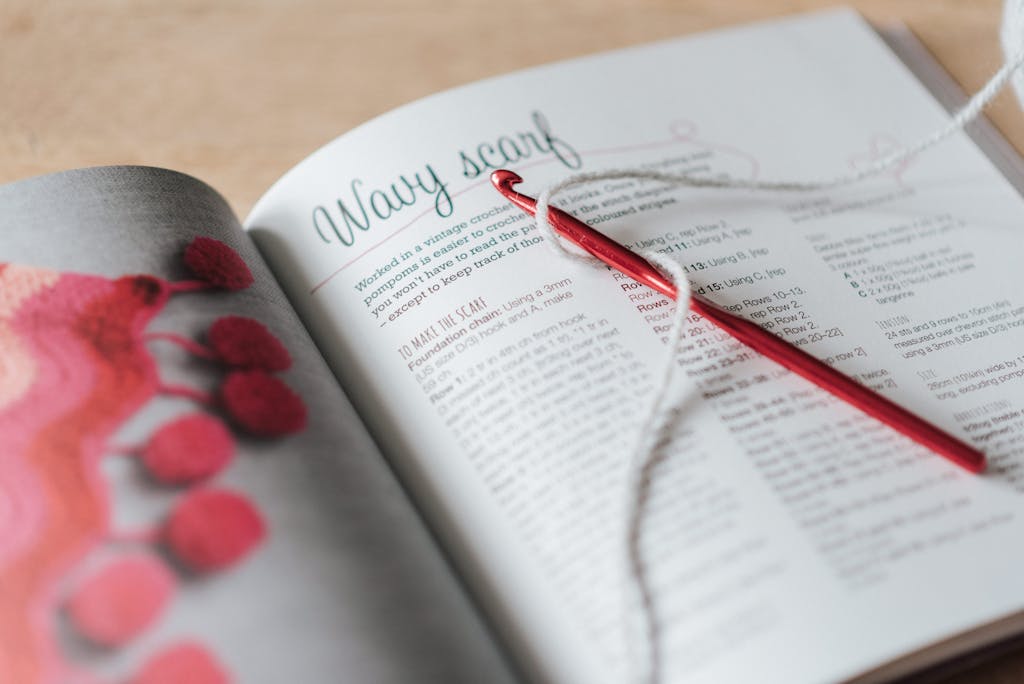 Close-up of a yarn and crochet needle on an open craft book, showcasing cozy DIY knitting.